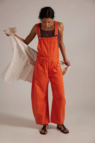 Person wearing bright orange overalls holding a striped garment against a plain background