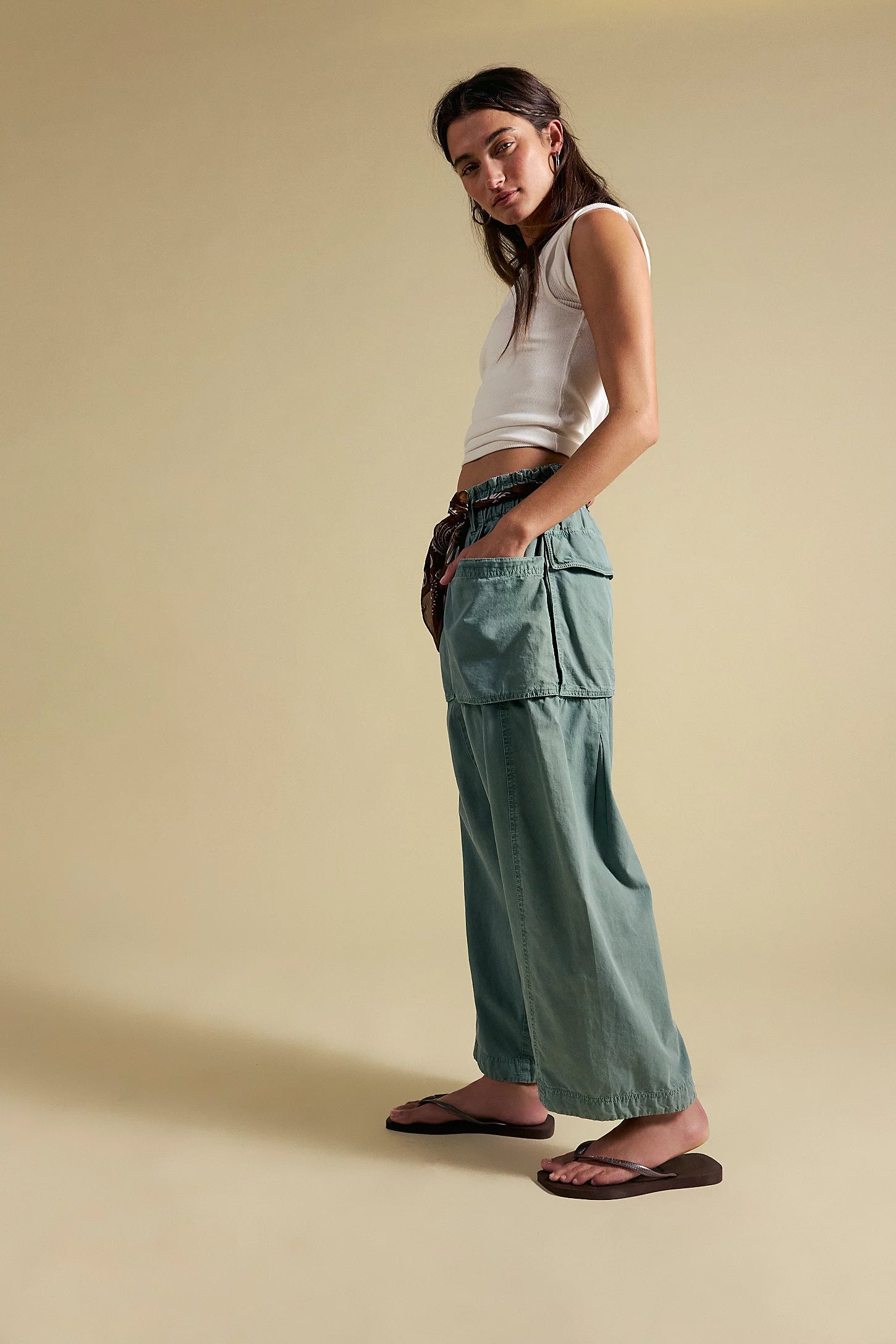 A women wearing light blue cargo harem pants on a neutral background. 