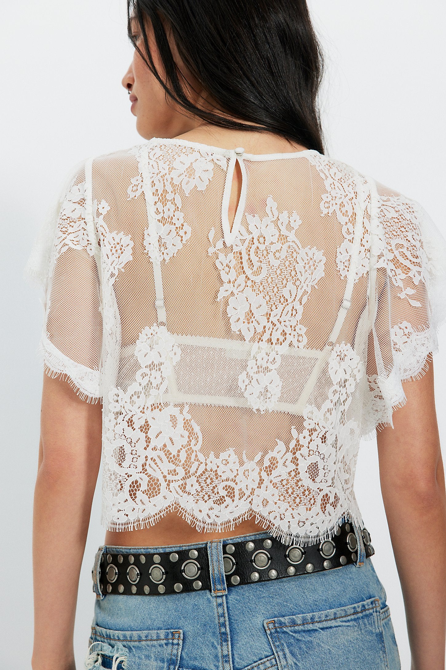 White lace top worn by a person on a white background