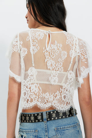 White lace top worn by a person on a white background