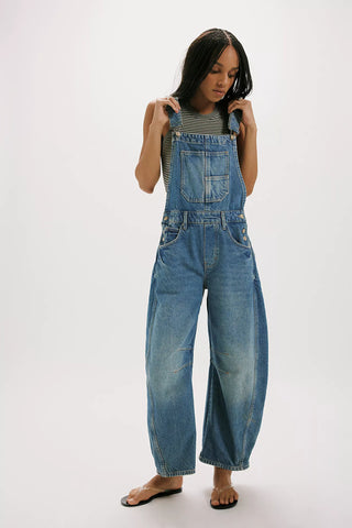 Person wearing blue denim overalls on a white background