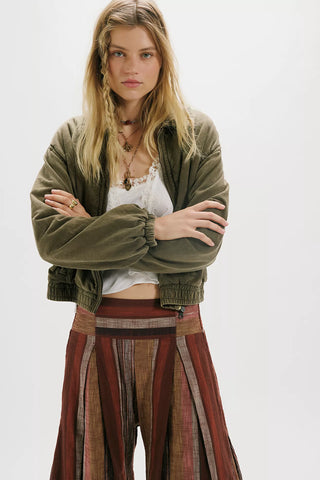 Woman wearing a green jacket and patterned skirt on a white background
