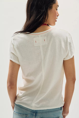 Person wearing a white t-shirt with a brand logo on a plain background