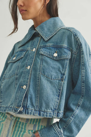Close-up of a person wearing a blue denim jacket on a light gray background