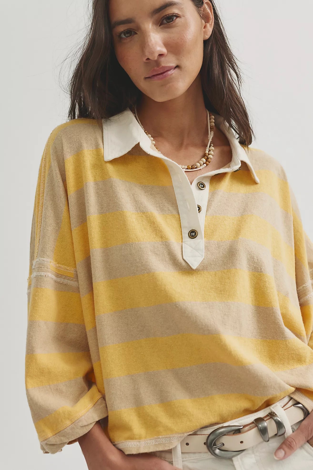 Woman wearing a yellow and beige striped shirt with a white collar.