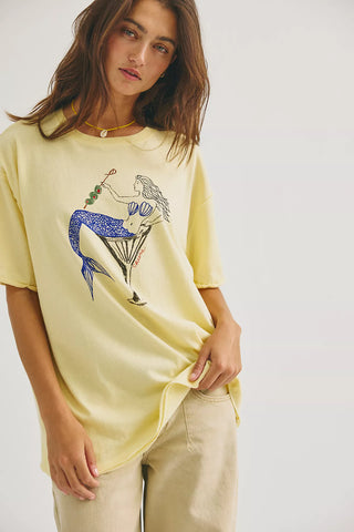 Woman wearing a yellow t-shirt with a graphic design on a plain background