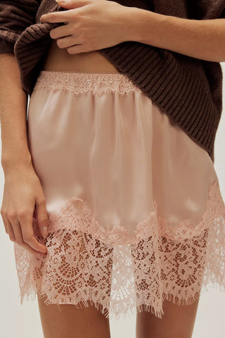 Person wearing a lace-trimmed satin skirt with a brown sweater.