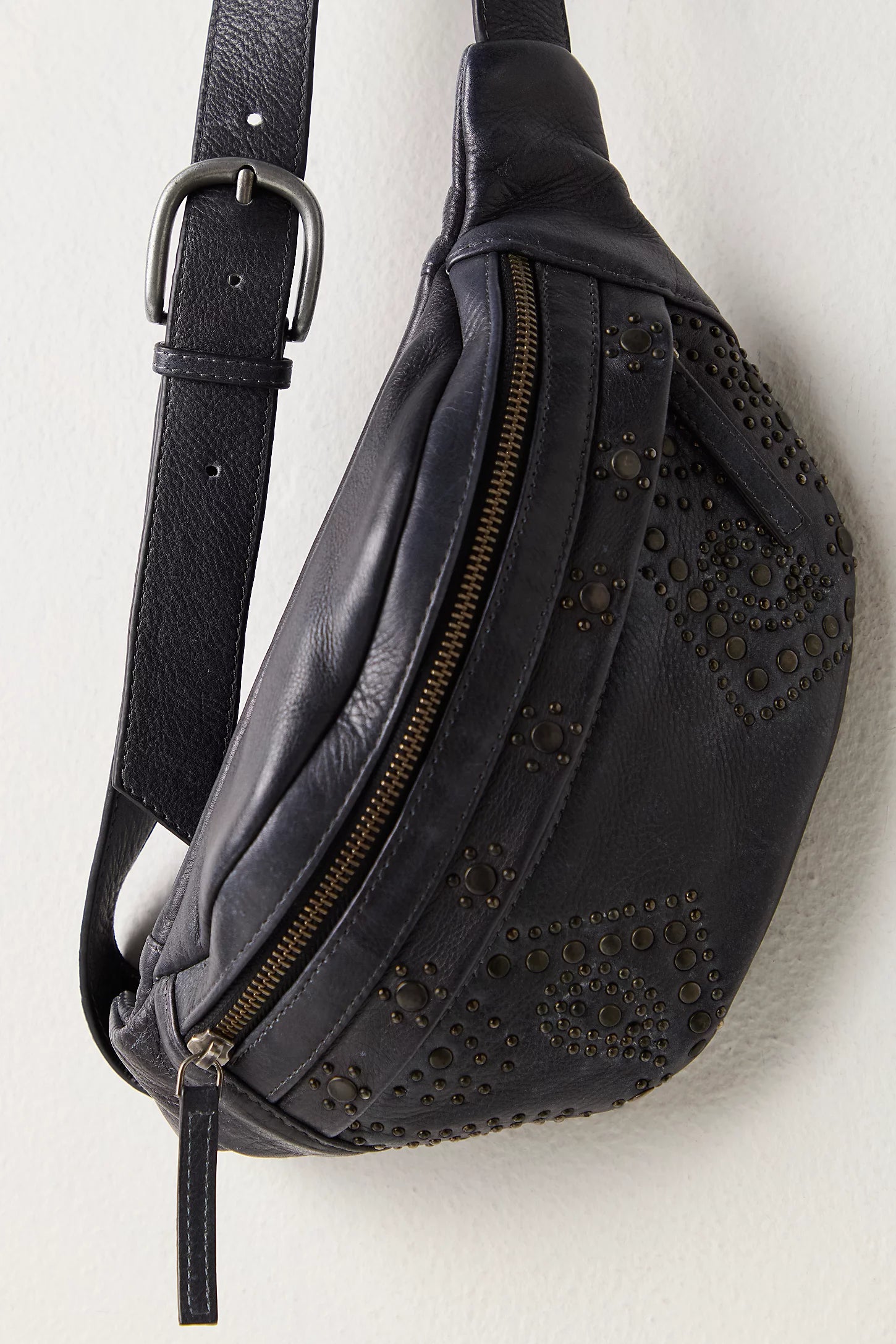 Black leather waist bag with studs on a light gray background