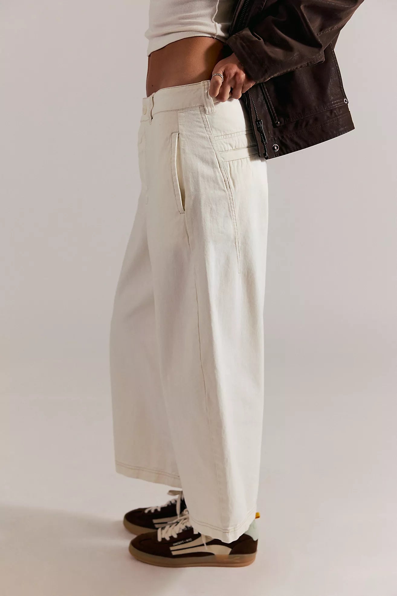 Person wearing white wide-leg pants with a plain background