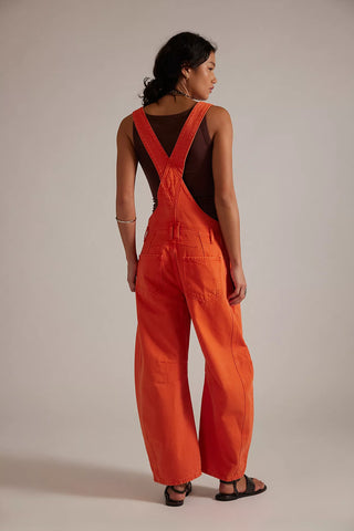 Person wearing bright orange overalls on a plain background