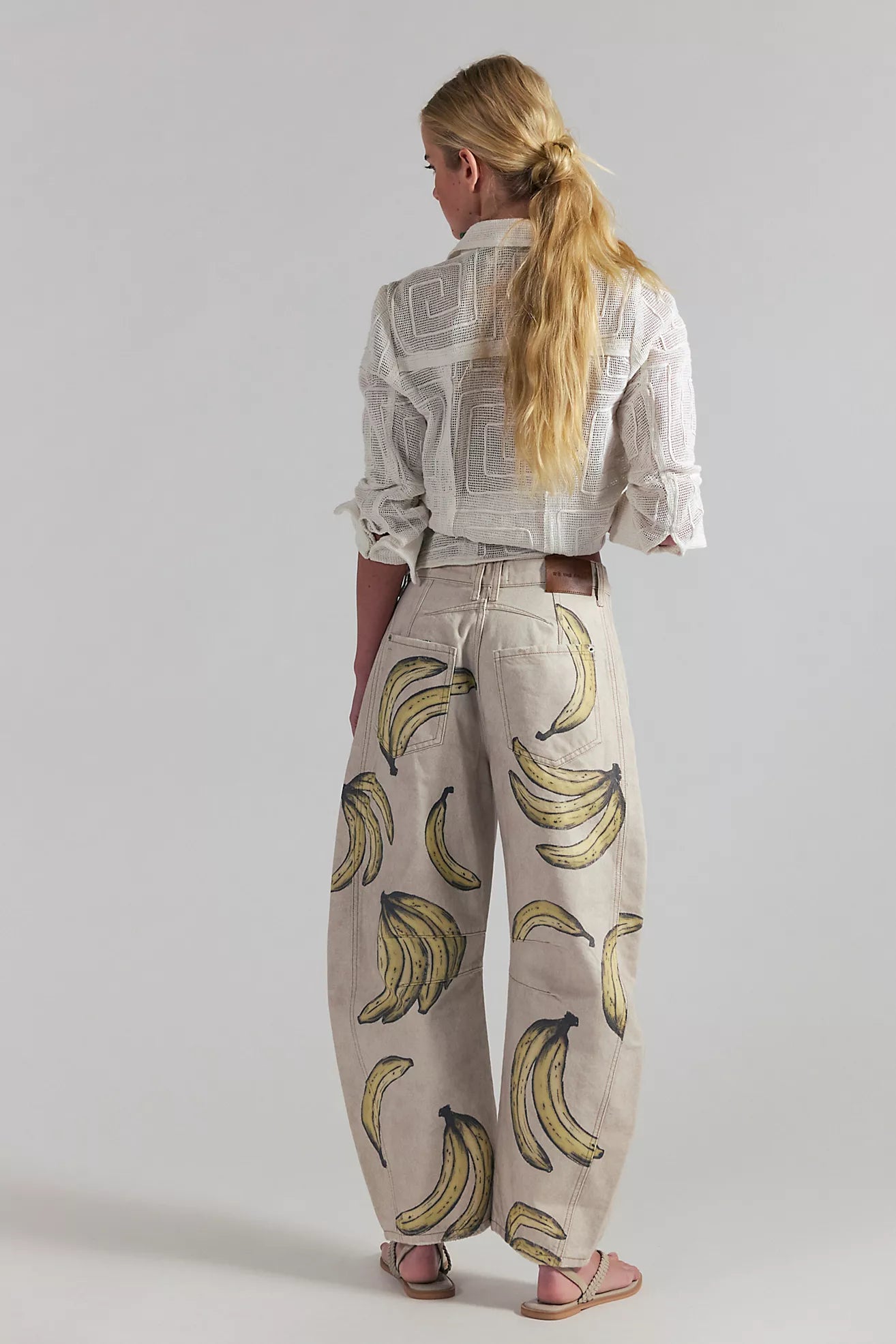 Person wearing a patterned shirt and banana print pants on a plain background