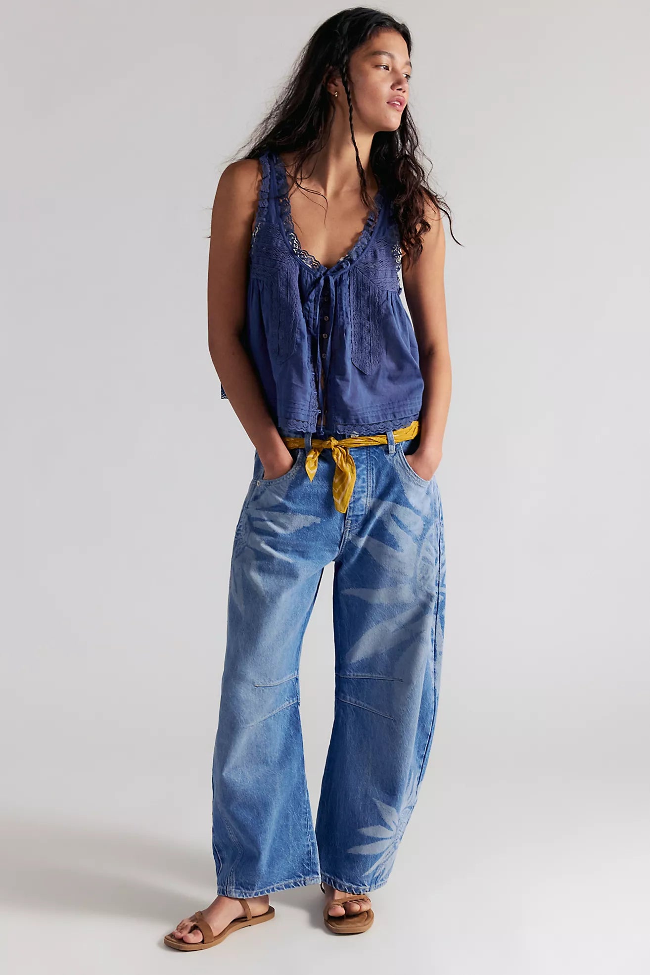 Woman wearing a blue denim jumpsuit with a yellow belt against a white background
