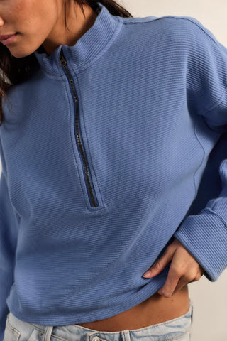 Person wearing a blue half-zip pullover against a neutral background