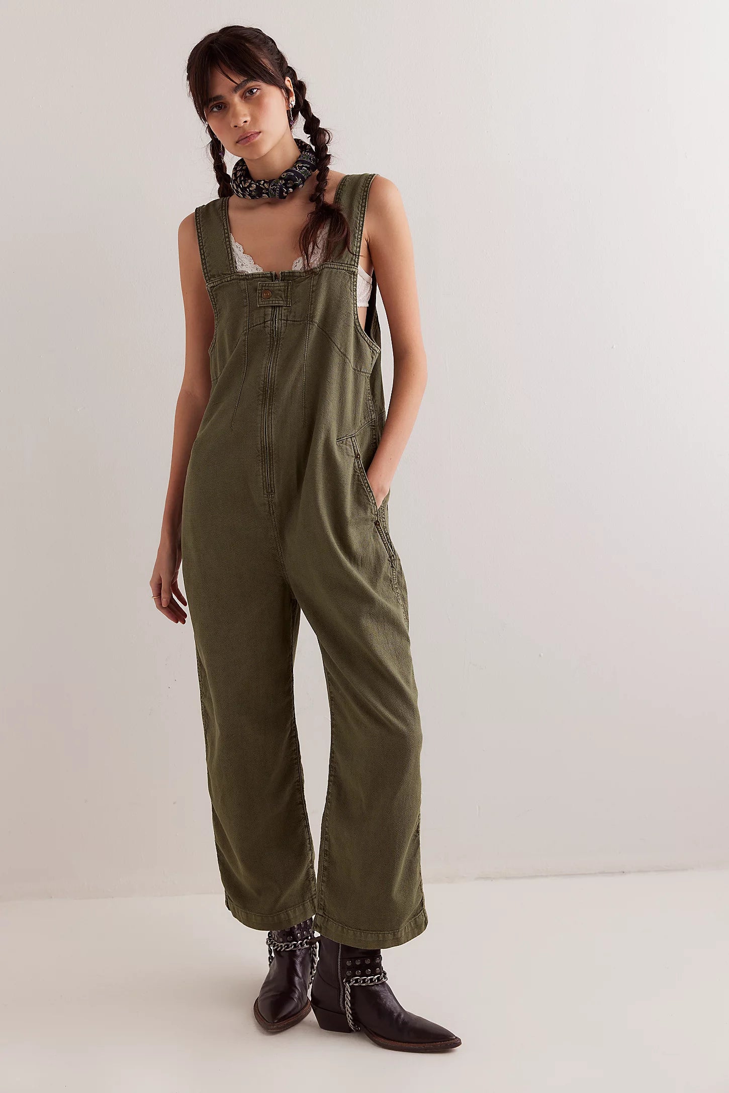 Woman wearing green overalls against a white background