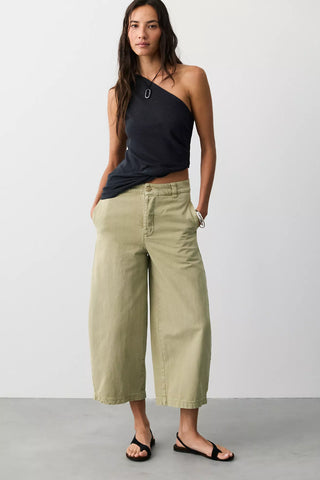 Women wearing green trousers on a neutral background.