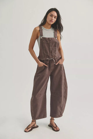 Woman wearing brown overalls on a plain background