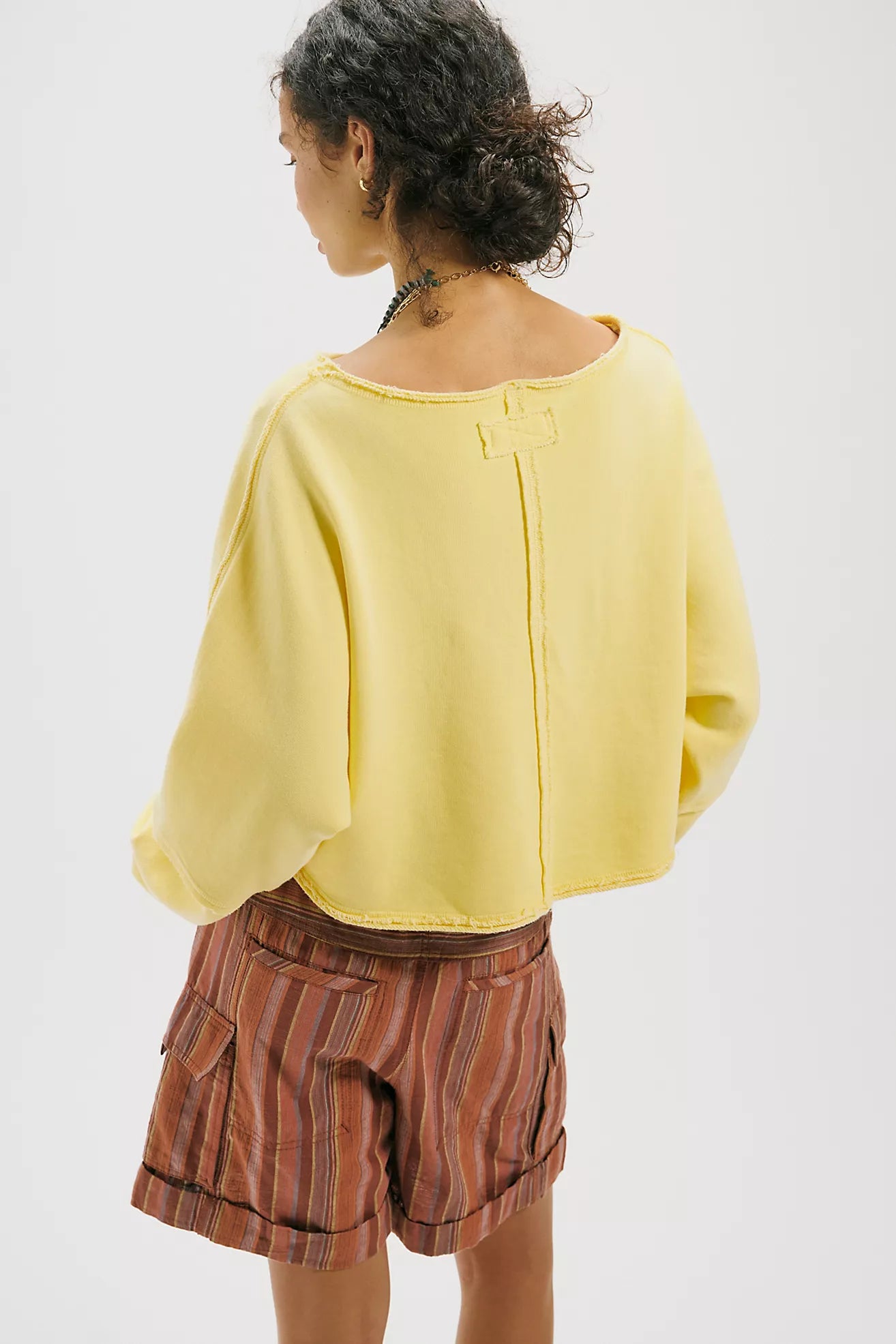 Person wearing a yellow top and striped shorts on a white background