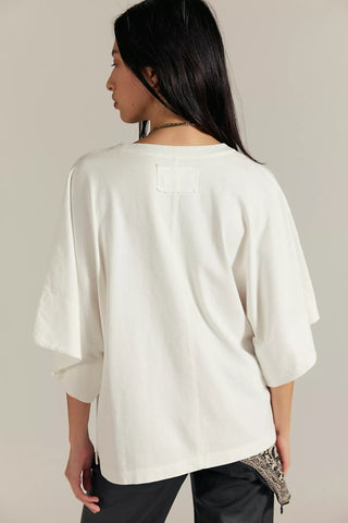Women wearing a white top against a neutral background.
