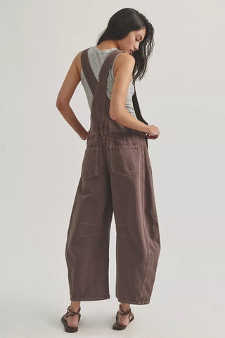 Woman wearing brown overalls on a plain background