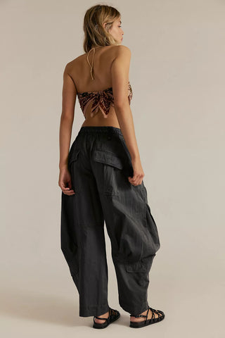 Woman wearing a brown top and black pants against a beige background