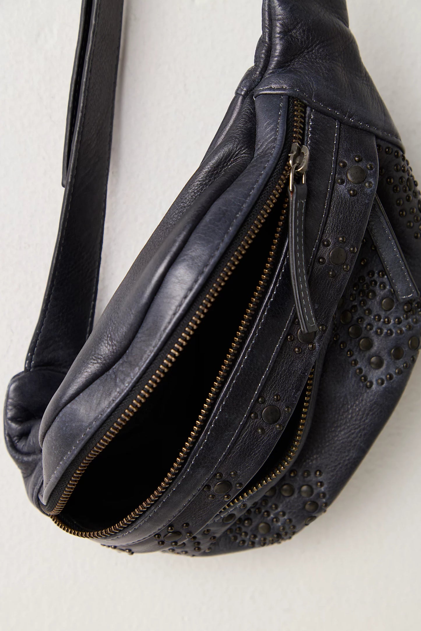 Black leather bag with studs and a zipper on a light gray background