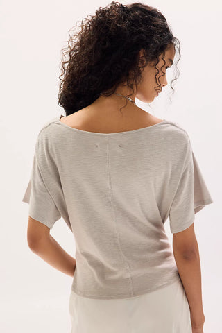 Woman wearing a beige top with a plain background
