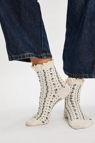 White socks with black polka dots worn with blue jeans on a white background
