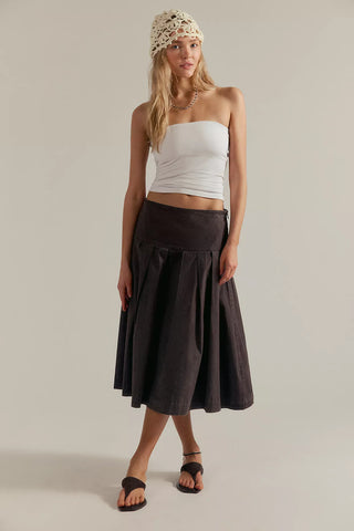 Woman wearing a white top and black skirt on a plain background