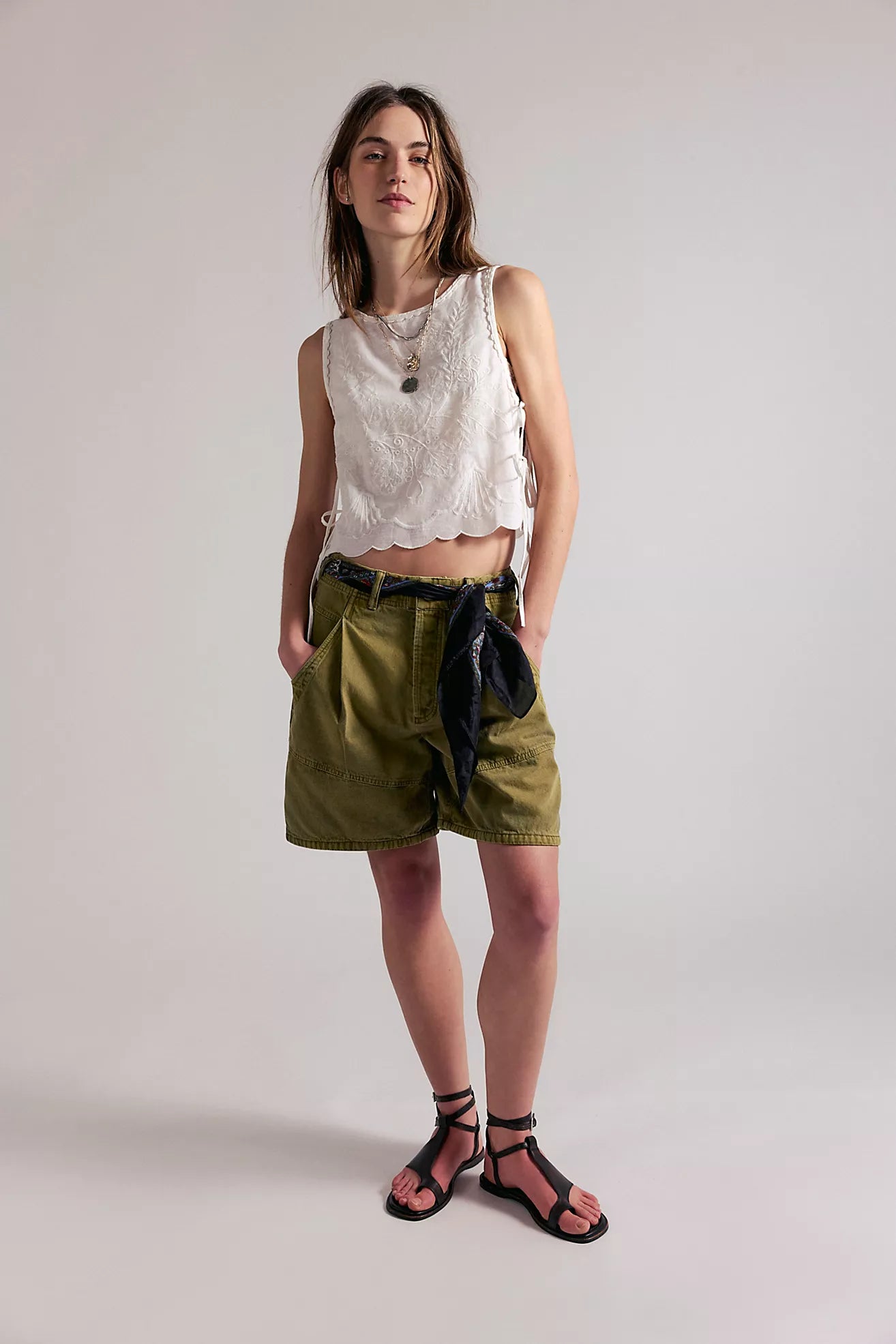 Woman wearing a sleeveless top and green shorts against a plain background