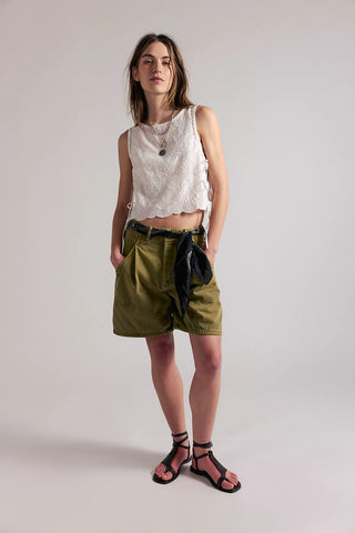 Woman wearing a sleeveless top and green shorts against a plain background