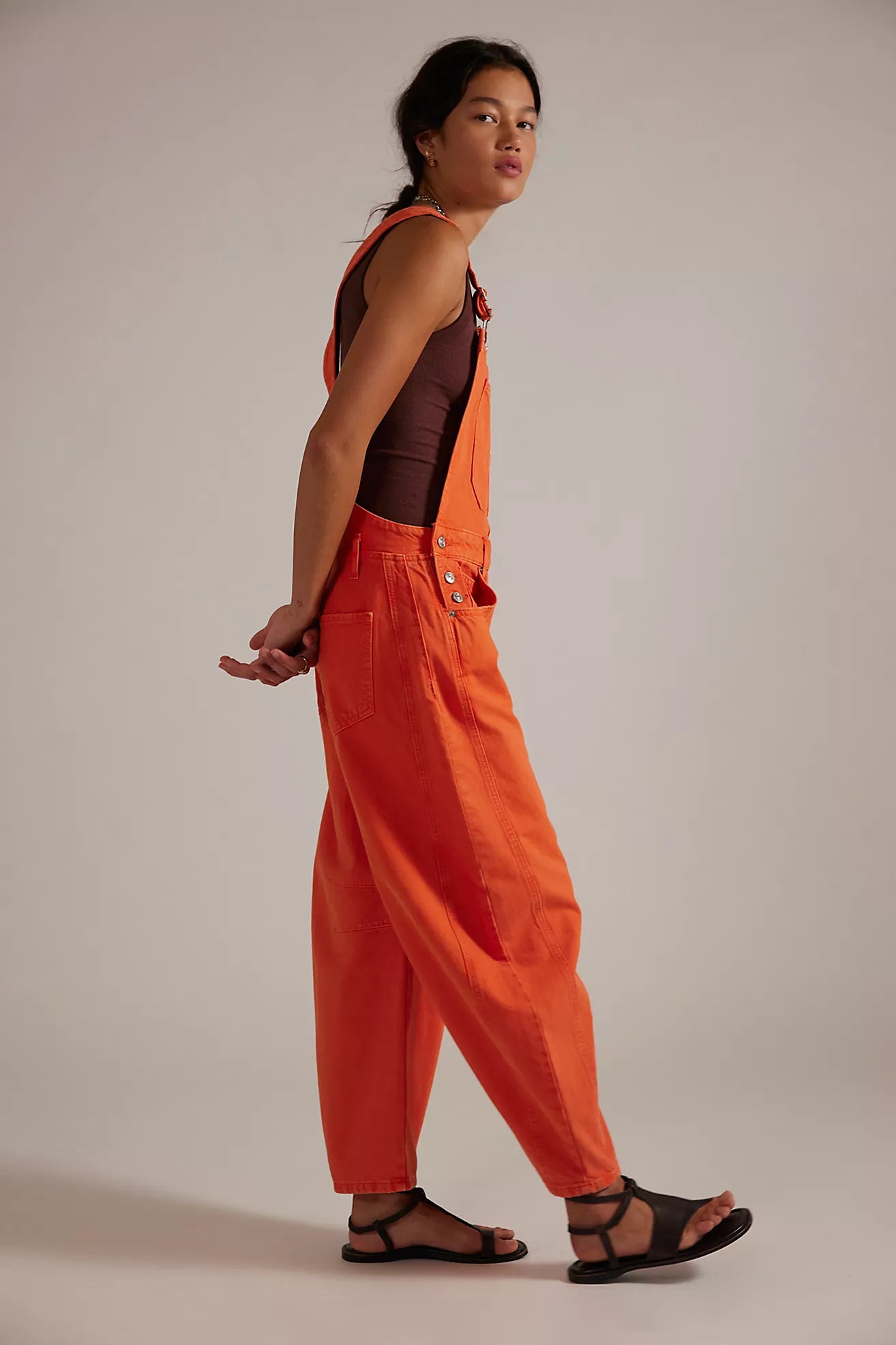 Person wearing orange overalls on a plain background