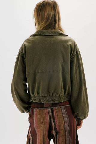 Person wearing a green jacket and striped pants on a white background