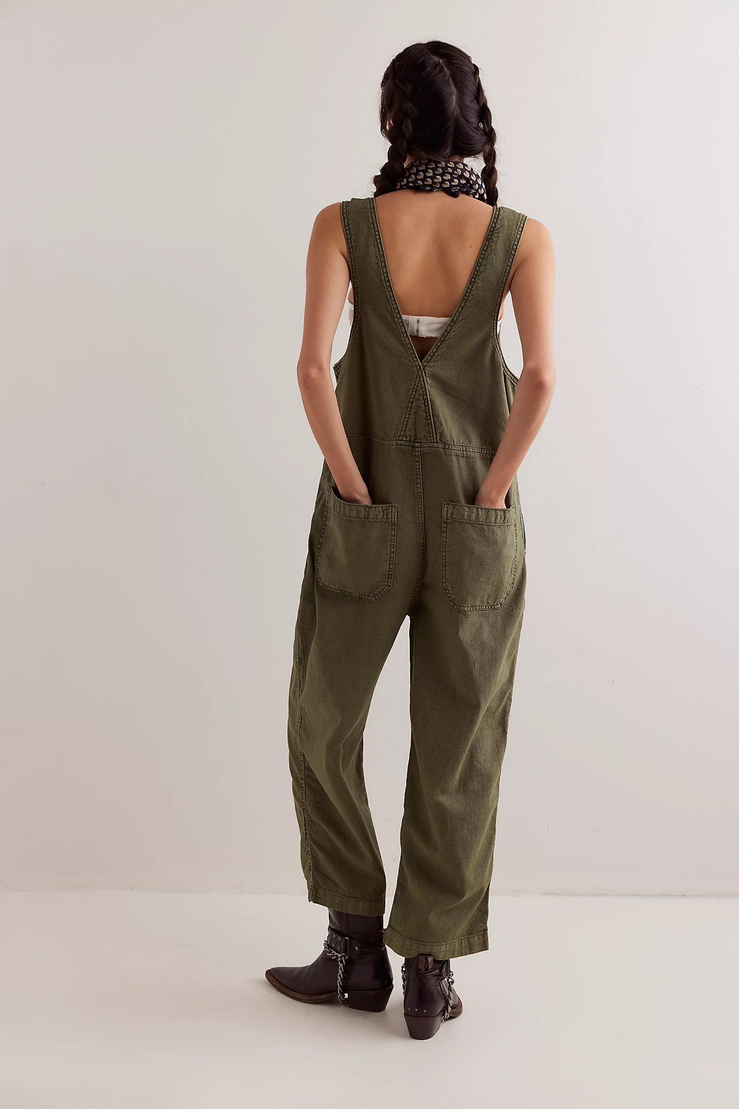 Person wearing green overalls from behind on a white background