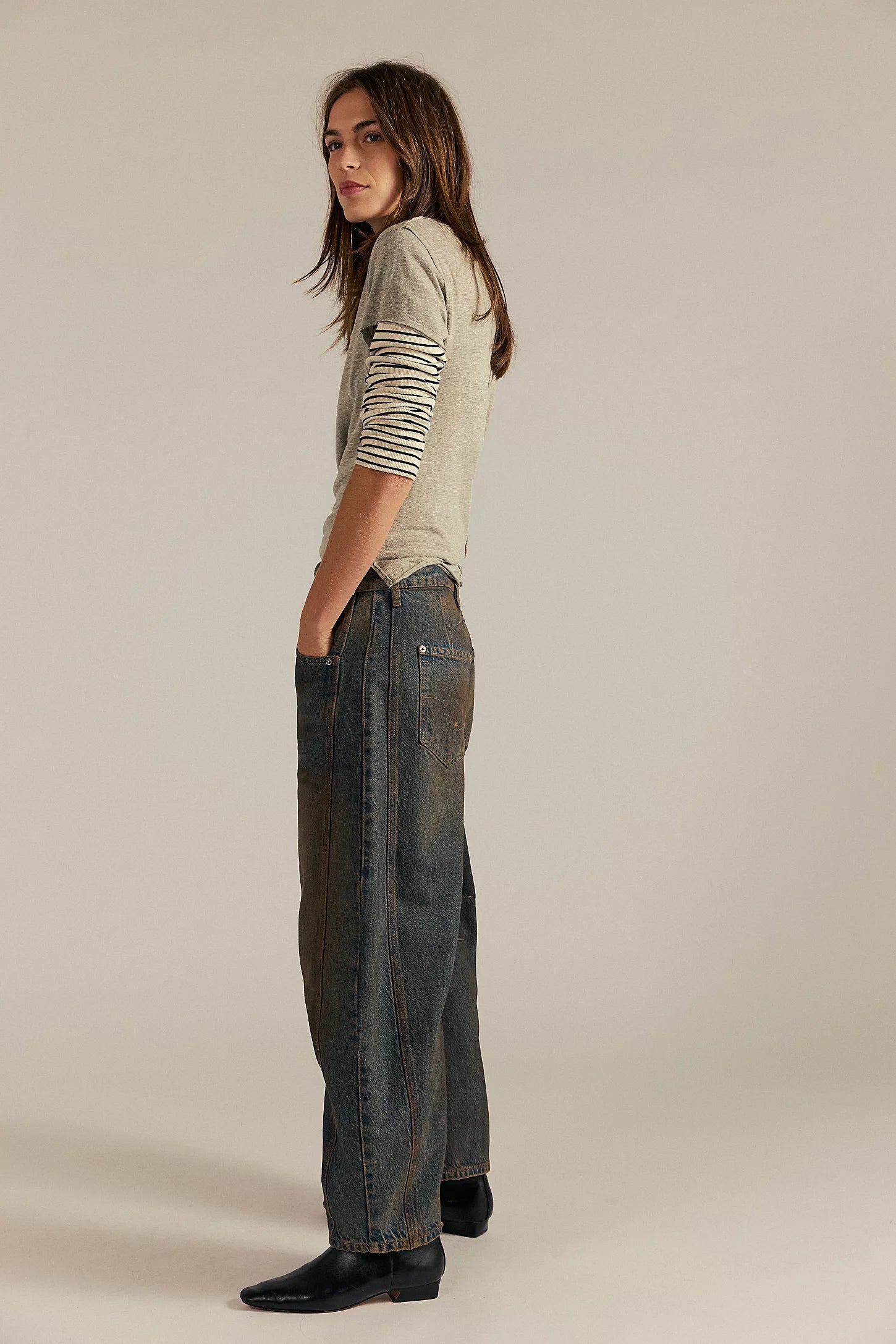 Woman wearing a light green shirt and dark jeans on a beige background