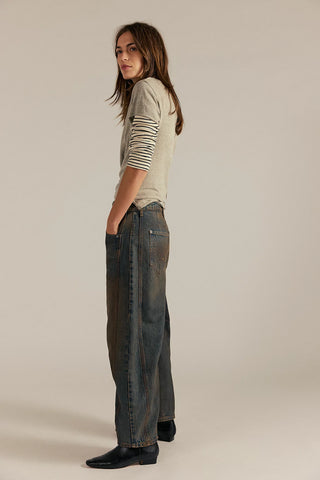 Woman wearing a light green shirt and dark jeans on a beige background