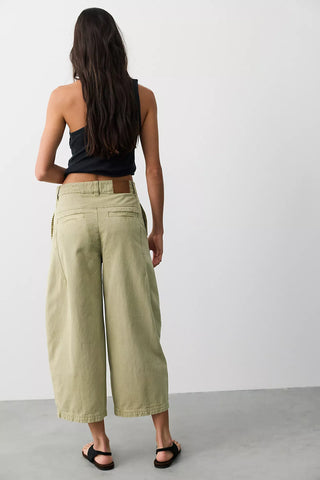 Women wearing green trousers on a neutral background.