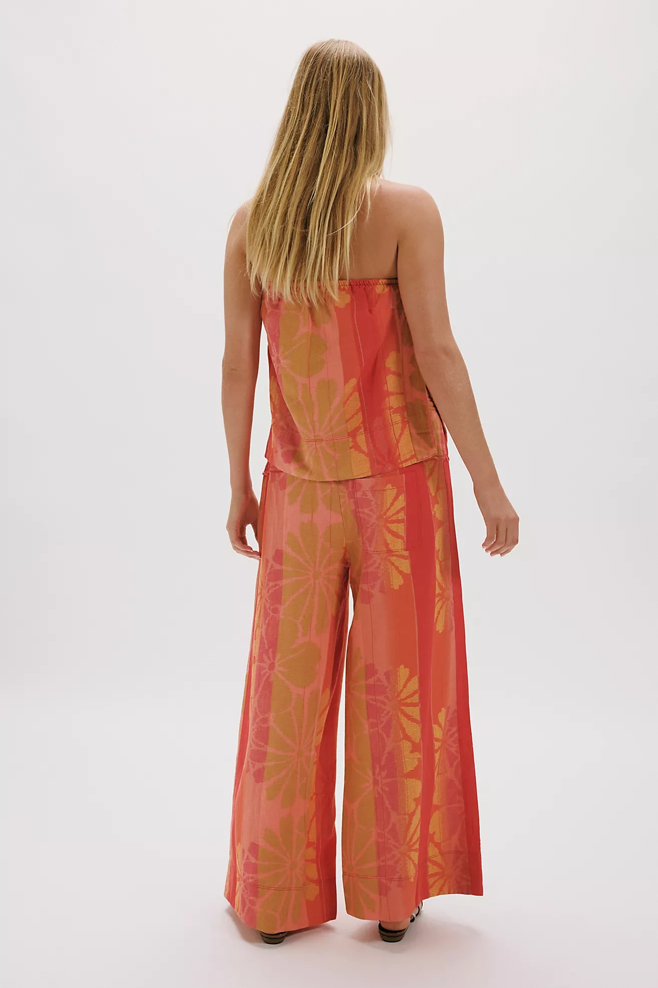 Woman wearing a red and orange patterned outfit on a white background