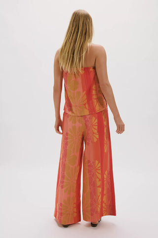 Woman wearing a red and orange patterned outfit on a white background