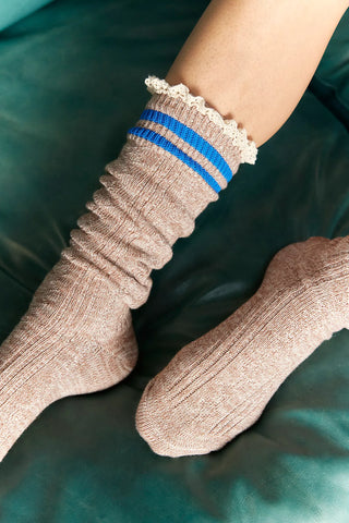 Beige socks with a blue stripe on a green surface