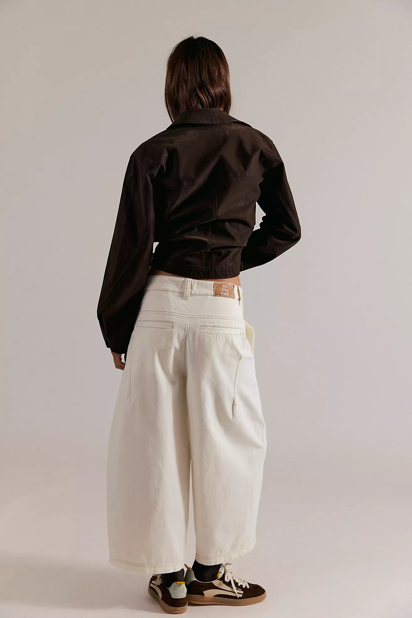 Person wearing a dark shirt and light-colored pants against a plain background
