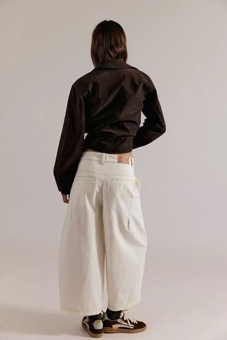 Person wearing a dark shirt and light-colored pants against a plain background