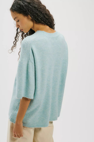 Woman wearing a light blue sweater against a white background