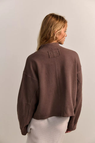 Person wearing a brown textured jacket on a plain background