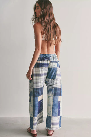 Woman wearing a patterned blue and white pants on a plain background