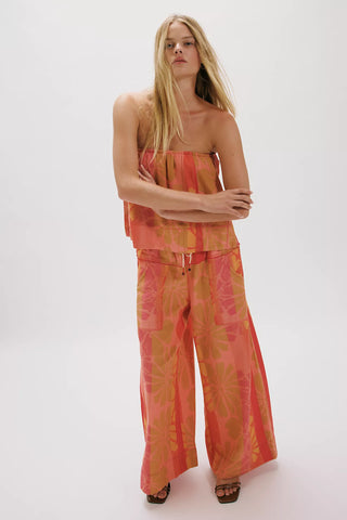 Woman wearing a colorful strapless top and wide-leg pants on a white background