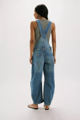 Person wearing blue denim overalls on a white background