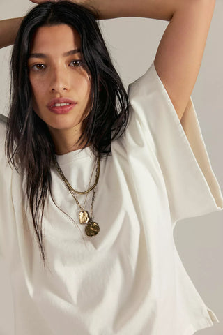 Women wearing a white top against a neutral background.