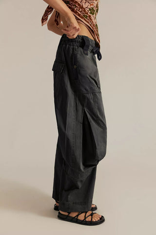 Person wearing black cargo pants on a beige background