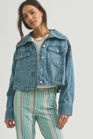Woman wearing a denim jacket and striped pants on a white background