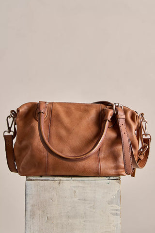 Brown leather handbag on a light gray surface with a neutral background